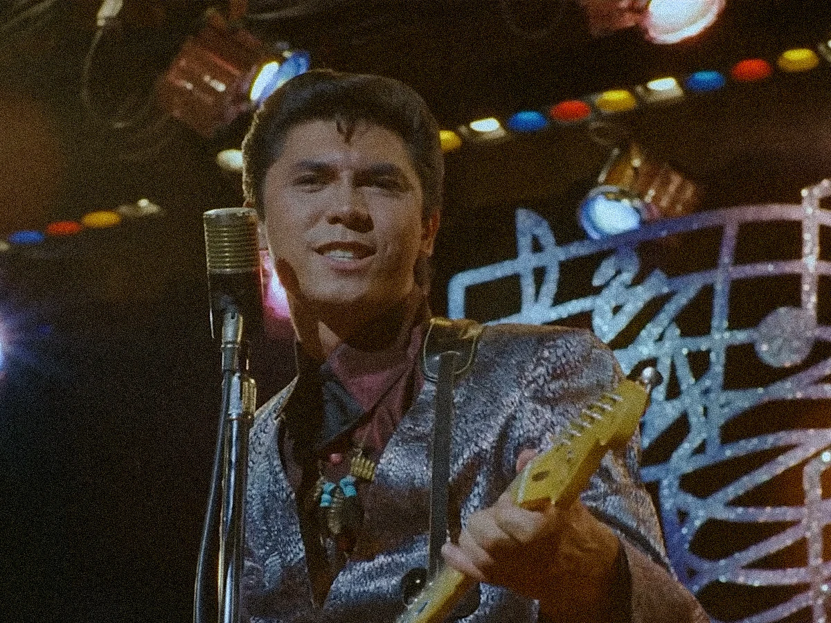 Lou Diamond Philips as Ritche Valens, playins a guitar on stage. (Still from La Bamba)